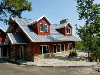 A home with red siding, a rock foundation,and a hardscaped yard area completed by Rock Country Masonry.