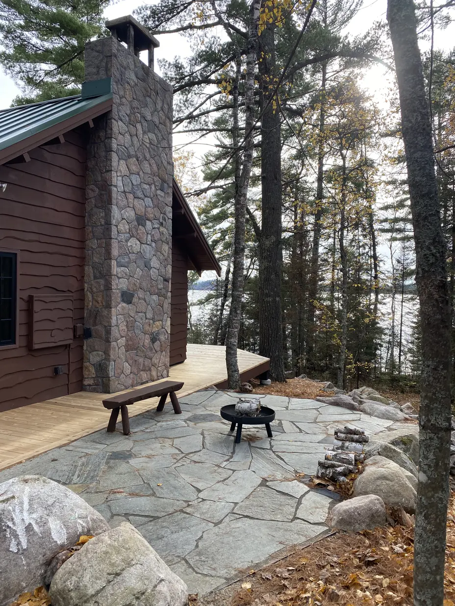 A home on a lake near Ely, Minnesota with a masonry rock chimney and a hardscaped patio.
