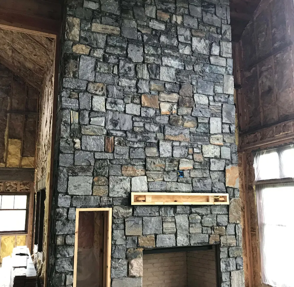 A large rock fireplace being built in a new home by Rock Country Masonry.